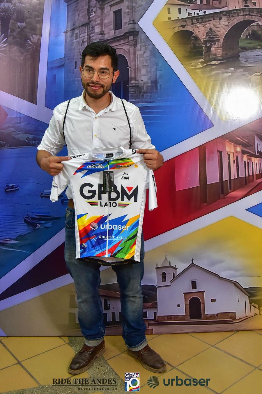 A participant holds up the official 2026 jersey at kit pickup in Duitama, with Ride The Andes on its front