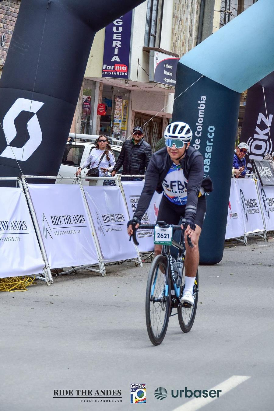 A rider crosses under the finish arch, with Ride The Andes banners along the barriers